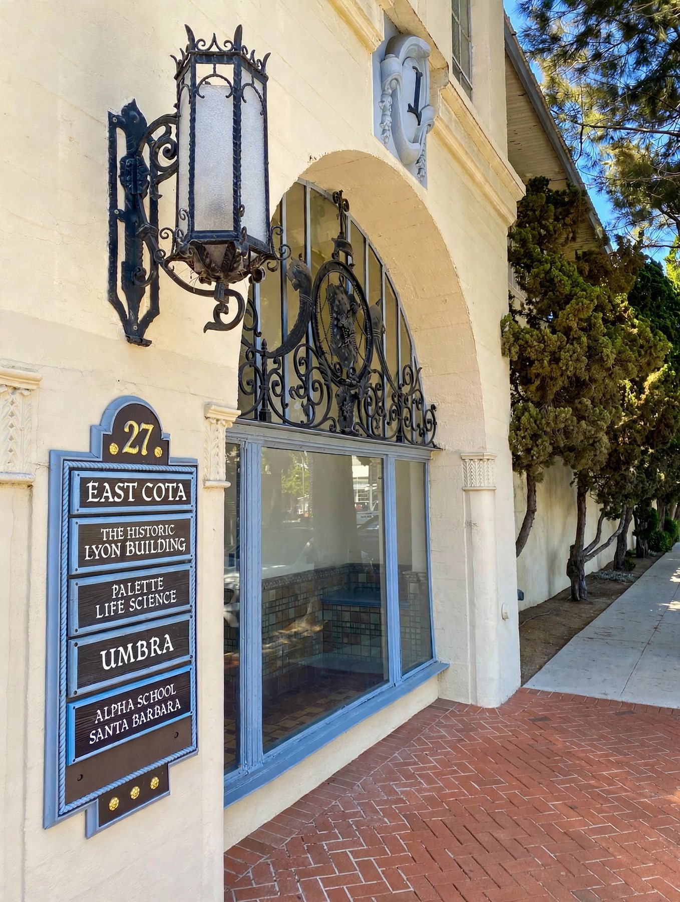The building's entrance sign and wrought-iron lantern beside an arched, iron-grilled window.