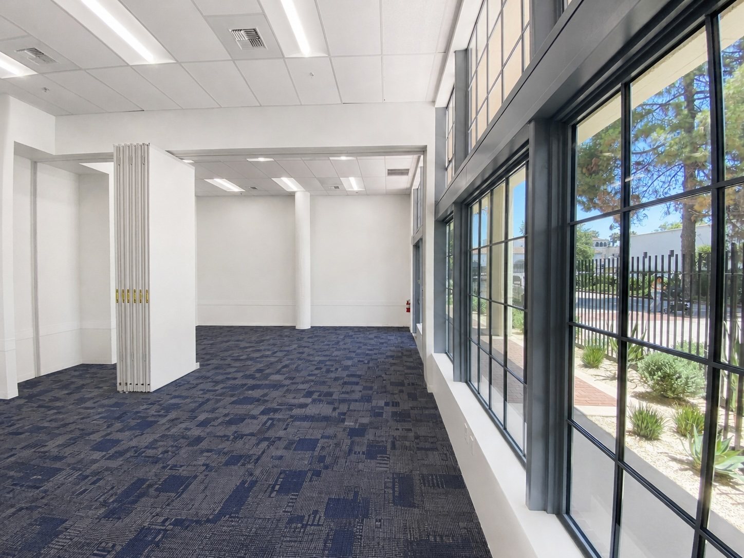 Suite 100 interior with a wall of steel-framed windows looking onto the landscaped walkway.