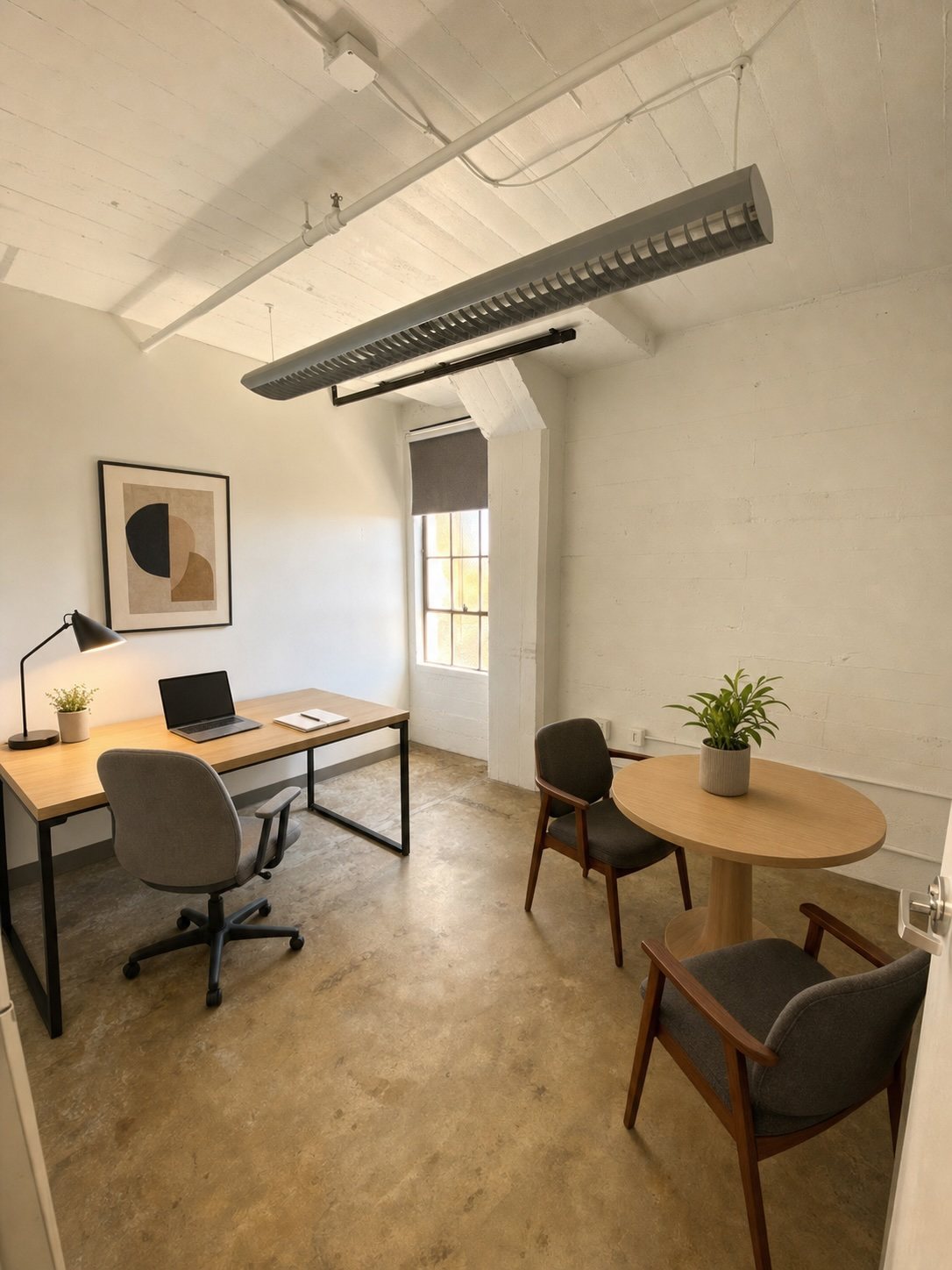 A compact Suite 300 office with a desk, round table and steel-framed window.