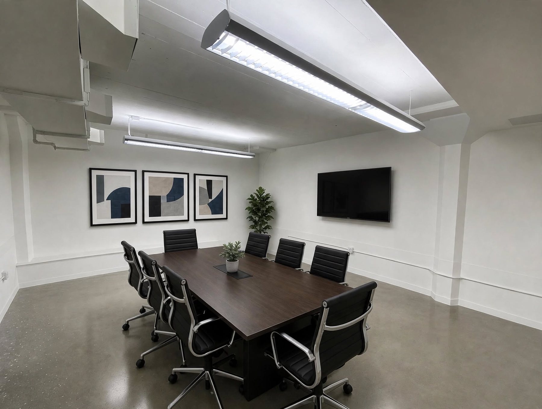 Suite 300 conference room with a long dark table, framed prints and a wall-mounted display.