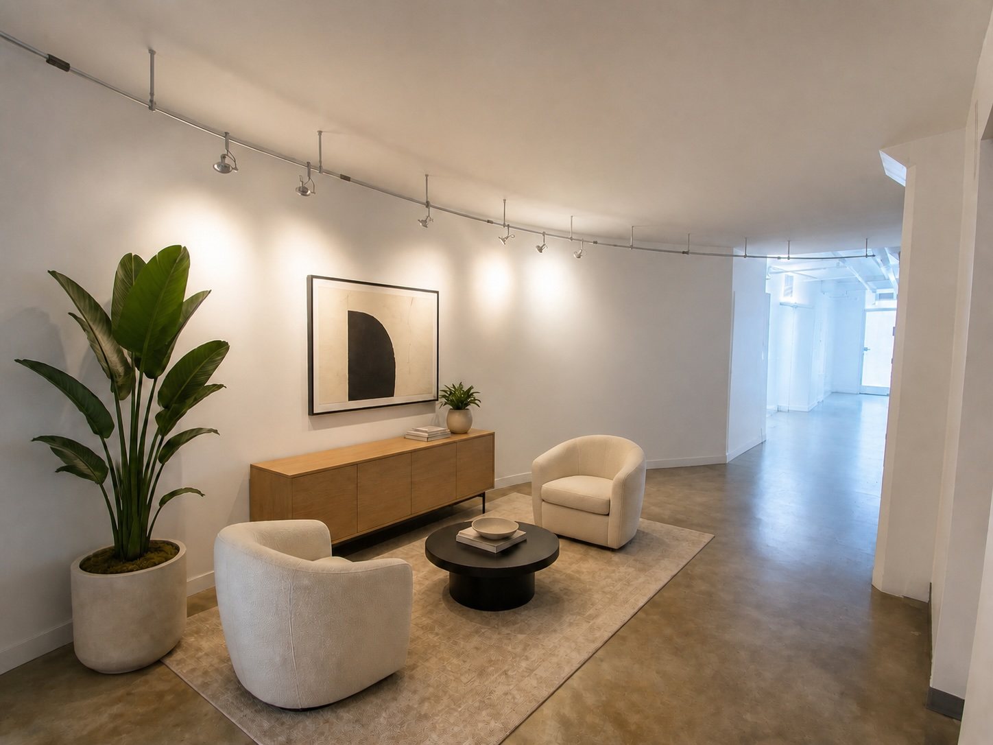 Suite 300 entry lounge with track lighting, a curved wall, credenza and two upholstered chairs.